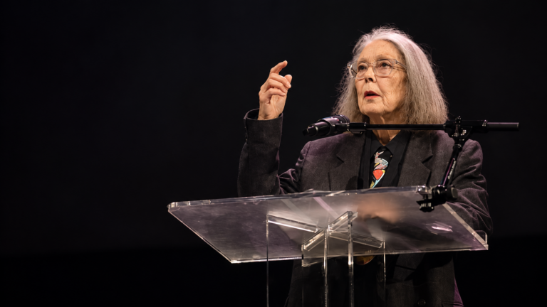 Anne Carson költő és író előadást tart egy pódiumon.
